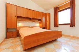 a bedroom with a bed with wooden cabinets and a window at Apartments Vlah in Medulin