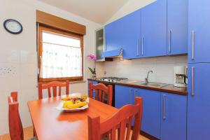 a kitchen with blue cabinets and a wooden table with a bowl of fruit at Apartments Vlah in Medulin