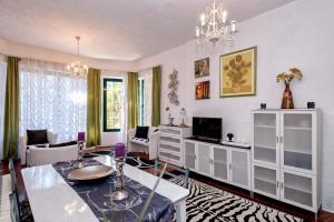 a living room with a dining table and a tv at Apartments Villa Domus Marini in Hvar