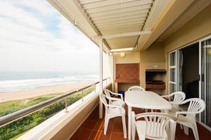 uma varanda com mesa e cadeiras e vista para a praia em Beachfront Apartments @ Amanzimtoti em Amanzimtoti