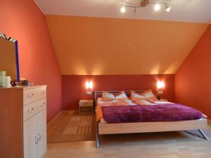 a bedroom with a bed with an orange wall at Apartment on the Moselle in Neumagen Dhron in Neumagen-Dhron