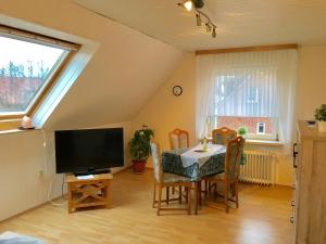 une salle à manger avec une table, des chaises et une télévision dans l'établissement Ferienwohnung Nordlicht, à Norden