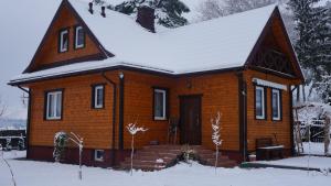 una pequeña casa de madera con nieve en el techo en Uroczysko Ostoja, en Kopisk