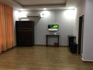 een kamer met een tv aan de muur en een tafel bij Grand Business Hotel in Jertih