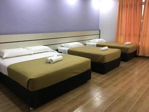 een kamer met drie bedden en handdoeken erop bij Grand Business Hotel in Jertih