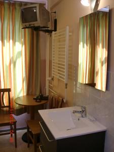 ein Badezimmer mit einem Waschbecken, einem Tisch und einem TV in der Unterkunft Budget Hotel Neutraal in Amsterdam
