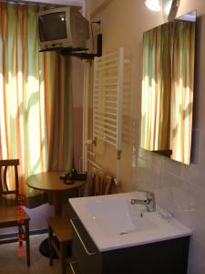 a bathroom with a sink and a table and a tv at Budget Hotel Neutraal in Amsterdam