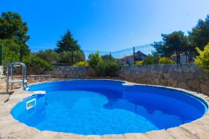 a large blue pool with a stone wall at Vila Jadranka in Vodice
