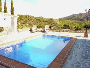 una gran piscina de agua azul frente a una montaña en Belvilla by OYO Casa El Cerro, en Viñuela