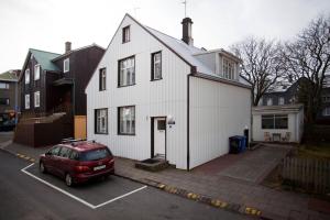 a red van parked in a parking lot in front of a white house at Aska Apartment in Reykjavík