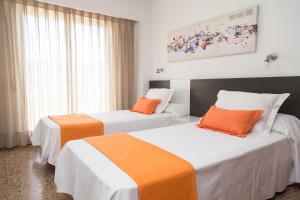 バレンシアにあるピオ XII アパートメンツ バレンシアのオレンジと白を基調としたホテルルーム内のベッド2台