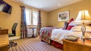 a bedroom with a bed, a desk, and a window at Hunday Manor Country House Hotel in Winscales