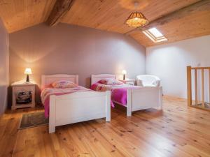 two beds in a room with wooden floors at Farmhouse with garden near Richelieu in Chaveignes