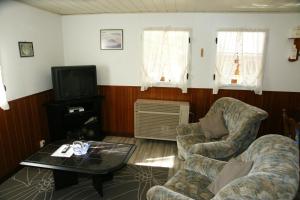 a living room with two chairs and a table and a tv at S.C.I. Rannerbaach in Dirbach