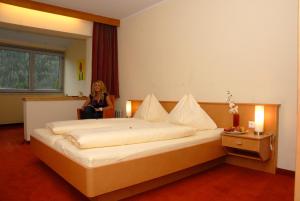 a woman in a hotel room with a large bed at Hotel Sonnenheim in Bad Kleinkirchheim