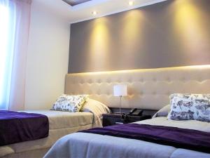 una habitación de hotel con 2 camas y una pared grande en Kitek Hotel Boutique en Mendoza