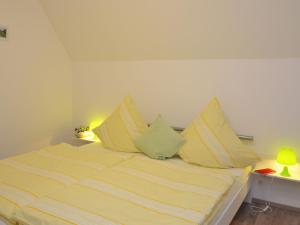 a bed with yellow and white striped sheets and pillows at Charming holiday home near the ski area in Schmallenberg