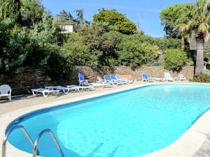 a swimming pool with lounge chairs and a palm tree at Boutique Holiday Home in Bormes les Mimosas with Pool in Bormes-les-Mimosas