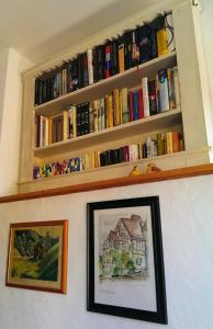 un estante de libros sobre una pared con libros en Hotel Villa Rossek, en Bad Liebenstein