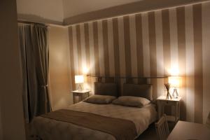 ein Schlafzimmer mit einem Bett mit gestreiften Wänden und 2 Lampen in der Unterkunft La Maison in Vallata