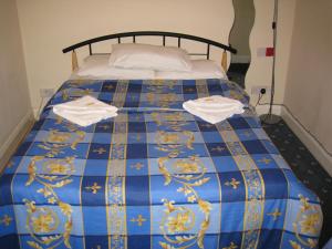 Una cama azul y dorada con dos toallas. en Hotel Sophia, en Londres