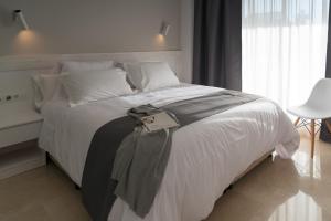 a bedroom with a white bed with a purse on it at Mediterraneo Sitges in Sitges