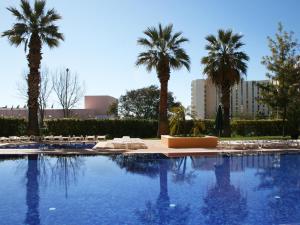 a large pool of water surrounded by palm trees at Dom Pedro Portobelo in Vilamoura
