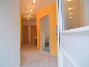 a hallway with orange walls and a white tile floor at Apartment in Ulmen near the lake in Ulmen