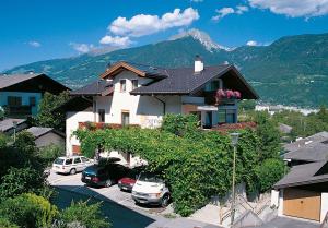 a house with cars parked in a parking lot with a mountain at Das Sonnenheim in Marlengo