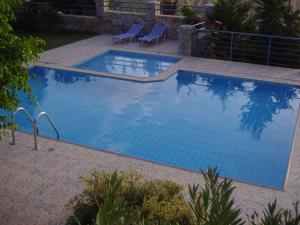 LefkogeiaにあるModish Villa in Lefkogia Crete with Swimming Poolの大きな青いスイミングプール(椅子2脚付)