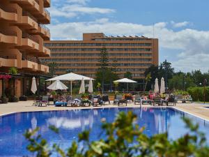 a swimming pool with tables and chairs and a building at Dom Pedro Portobelo in Vilamoura