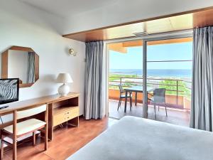 a hotel room with a bed, table, chairs and a window at Dom Pedro Portobelo in Vilamoura