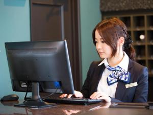 a woman sitting at a desk with a computer at Hotel AreaOne Nobeoka in Nobeoka