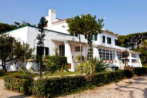 a white house with trees in front of it at Il Miraggio in Fregene