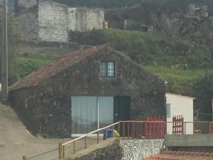 a stone house with a window and a fence at House with Forest View in Lajes das Flores