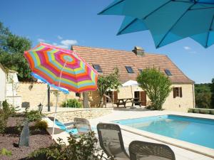Villefranche-du-PérigordにあるSuperb Holiday Home in Busse with Swimming Poolのスイミングプールの横にあるカラフルなパラソルと椅子