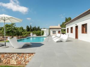 a patio with white chairs and a swimming pool at Belvilla by OYO Calet in Muro
