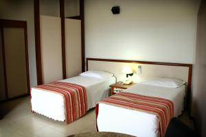 ein Hotelzimmer mit 2 Betten und einem Tisch mit einer Lampe in der Unterkunft Hotel Beira Rio in Itumbiara