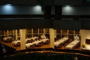 a dining room with white tables and chairs in a building at Hotel Beira Rio in Itumbiara