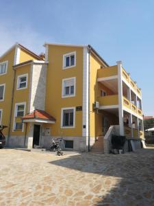 a yellow building on the beach with a motorcycle in front at Apartments Lili in Zadar