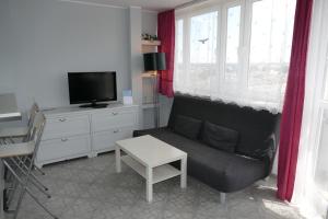 sala de estar con sofá, TV y mesa en Apartamenty Olimp, en Gdansk