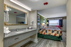 
a bathroom with a sink, mirror, and bathtub at Beachcomber Inn & Suites in Myrtle Beach

