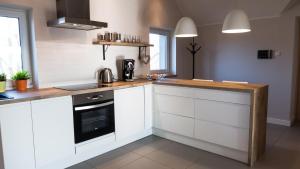 a kitchen with white cabinets and a wooden counter top at Apartament Jelitkowo in Gdańsk