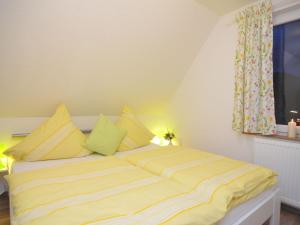 a yellow bed with yellow pillows and a window at Holiday home in Schmallenberg near a ski resort in Schmallenberg