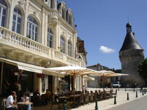 un restaurant avec des tables et des parasols en face d'un bâtiment dans l'établissement Hostellerie du Coq d'Or, à Jonzac