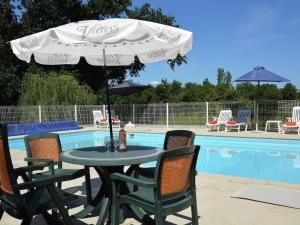 una mesa con sombrilla junto a la piscina en Traditional villa with pool en Estang