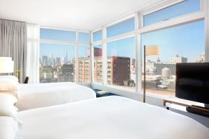 two beds in a hotel room with a large window at The Standard - East Village in New York