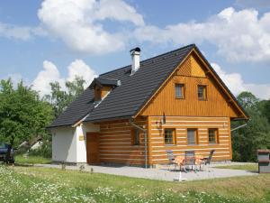 a log cabin with a black roof and chairs at Snarf in Jilemnice