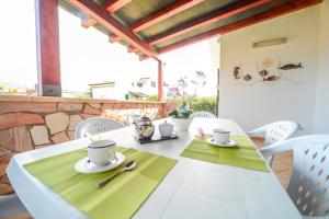 una mesa blanca con una servilleta verde y dos tazas en Case Vacanze Mare Nostrum - Villas in front of the Beach with Pool, en Campofelice di Roccella
