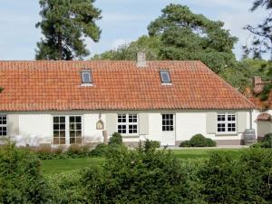 une maison blanche avec un toit orange dans l'établissement Elegant Holiday Home in Koksijde with Sauna, à Coxyde